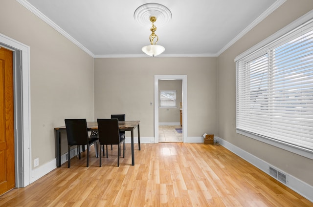 dining area featuring light wood finished floors, visible vents, and ornamental molding