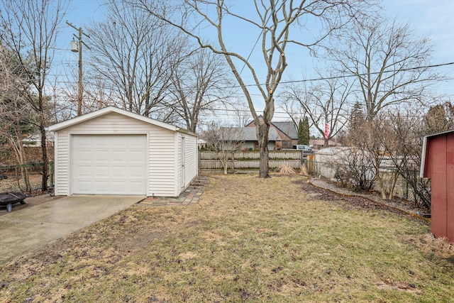 view of yard with an outbuilding, concrete driveway, a garage, and fence