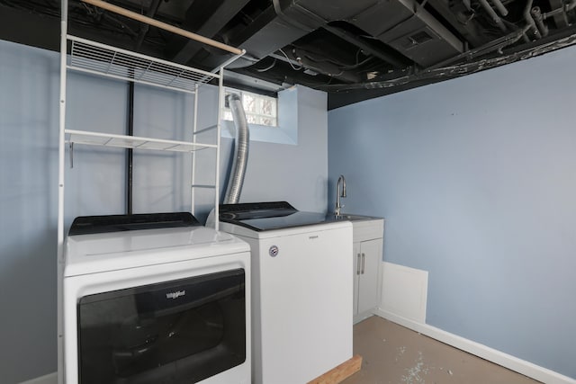 clothes washing area with cabinet space, washing machine and dryer, baseboards, and a sink