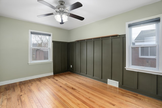 spare room with visible vents, light wood-style flooring, baseboards, and ceiling fan