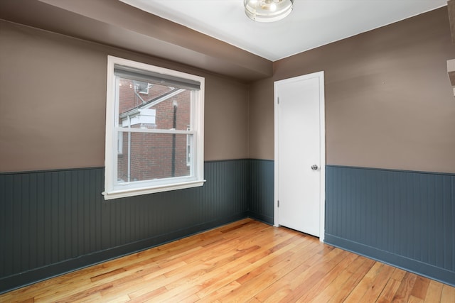 unfurnished room with hardwood / wood-style flooring and wainscoting