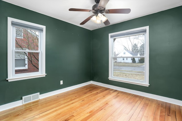 empty room with baseboards, visible vents, a wealth of natural light, and light wood-type flooring