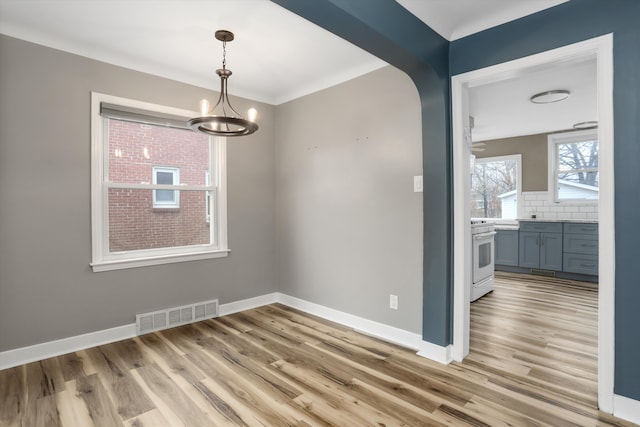 unfurnished dining area featuring an inviting chandelier, baseboards, visible vents, and light wood-type flooring