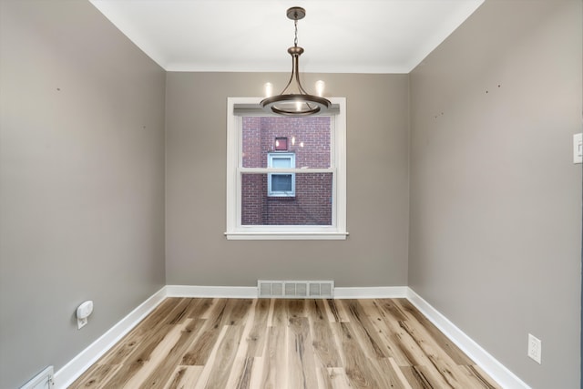 empty room with baseboards, visible vents, and light wood finished floors