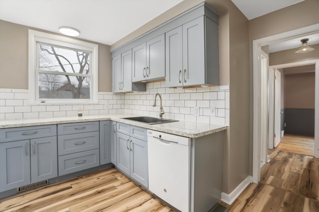 kitchen with gray cabinetry, visible vents, white dishwasher, and a sink