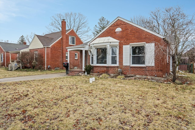 bungalow-style house featuring brick siding, a chimney, and a front lawn