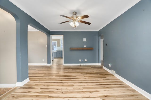 unfurnished room featuring ceiling fan, wood finished floors, arched walkways, and baseboards