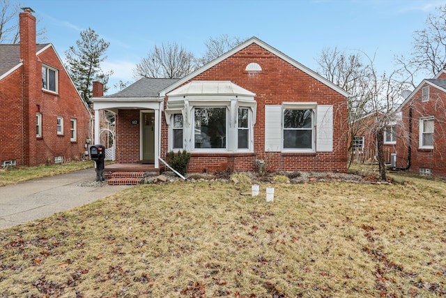 bungalow-style home featuring central air condition unit, brick siding, and a front lawn