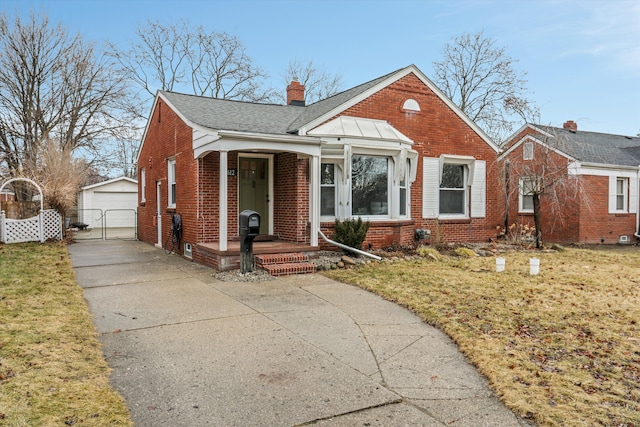 bungalow-style home with a front lawn, covered porch, an outdoor structure, brick siding, and a chimney