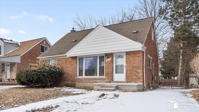 view of front of property featuring roof with shingles, a chimney, fence, and brick siding