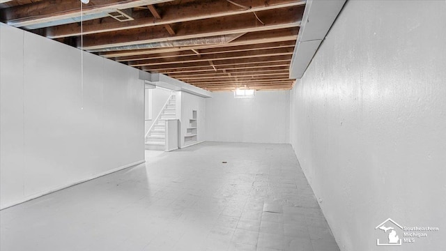 finished basement with stairway and tile patterned floors