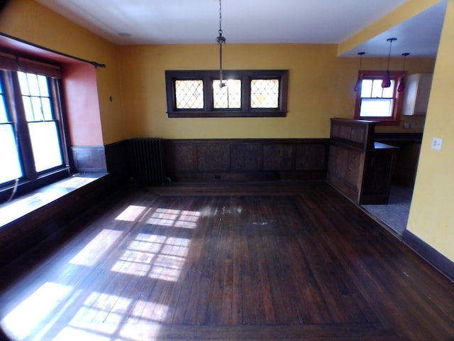 unfurnished dining area featuring radiator, dark wood-style floors, and wainscoting