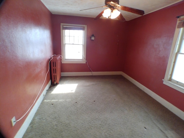 empty room featuring a ceiling fan, radiator, and baseboards