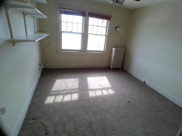 unfurnished room with light carpet, radiator heating unit, a ceiling fan, and baseboards