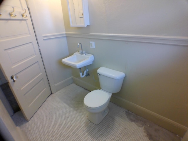 half bath with toilet, baseboards, and a sink