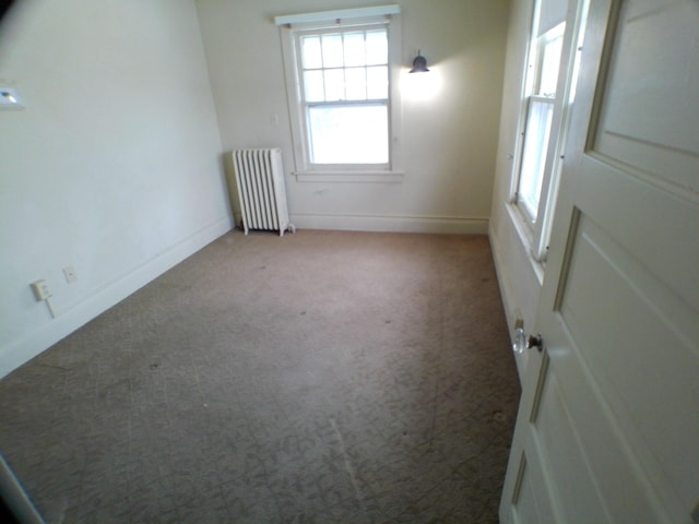 carpeted spare room with radiator heating unit and baseboards