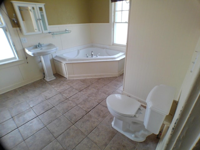 full bathroom with a healthy amount of sunlight, a garden tub, tile patterned flooring, and toilet