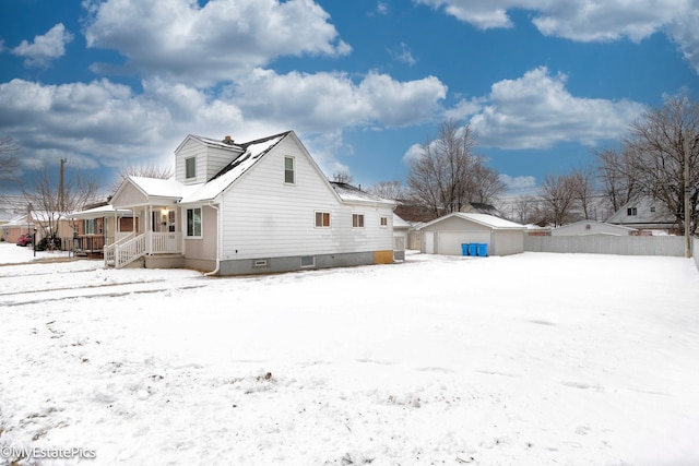 view of snow covered exterior featuring a garage, a porch, and an outdoor structure