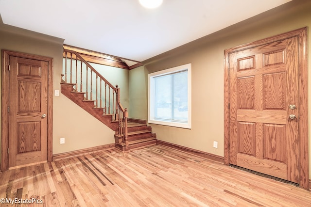 entrance foyer with crown molding, stairway, wood finished floors, and baseboards