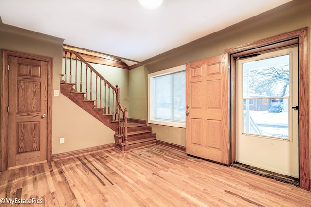 entrance foyer with stairs, ornamental molding, baseboards, and light wood-style floors