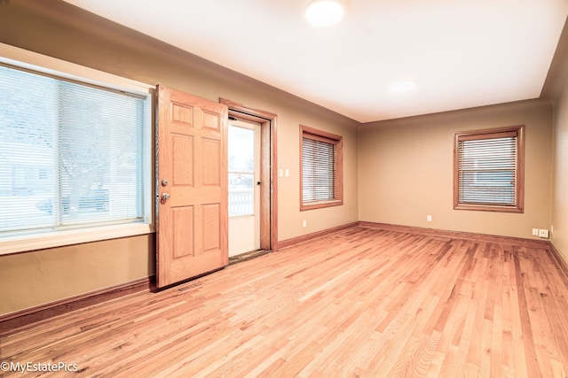 unfurnished room featuring baseboards, visible vents, and light wood finished floors