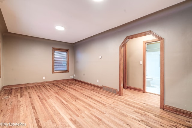 empty room with visible vents, light wood-style flooring, and baseboards