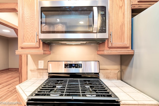 kitchen with tile countertops, light brown cabinetry, and appliances with stainless steel finishes