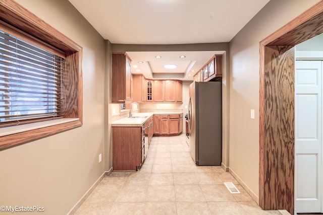 kitchen featuring light countertops, visible vents, glass insert cabinets, freestanding refrigerator, and a sink