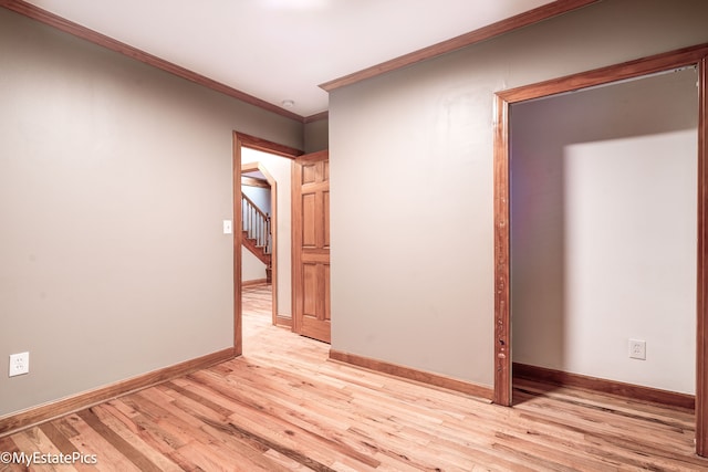 spare room with crown molding, light wood-style flooring, and baseboards