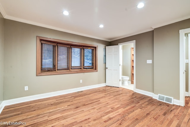 spare room featuring light wood-style floors, visible vents, ornamental molding, and baseboards