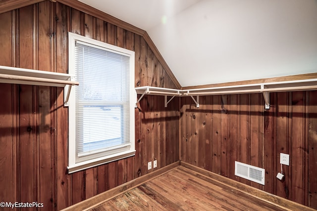 walk in closet with visible vents, vaulted ceiling, and wood finished floors