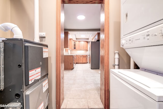 washroom with laundry area, light tile patterned floors, a sink, and stacked washer and clothes dryer