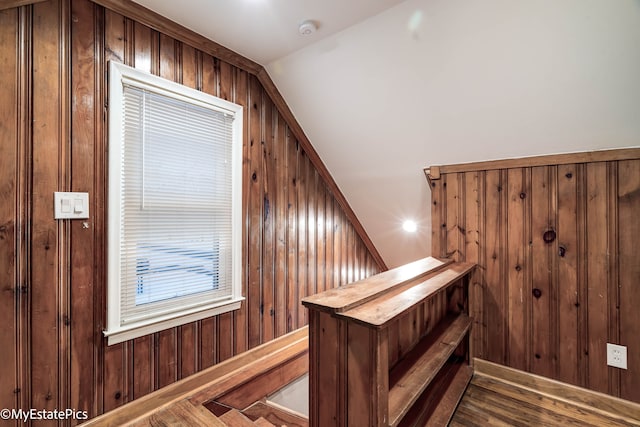 interior space featuring lofted ceiling, wooden walls, and wood finished floors