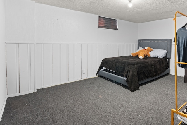 bedroom with dark carpet, a textured ceiling, and wainscoting