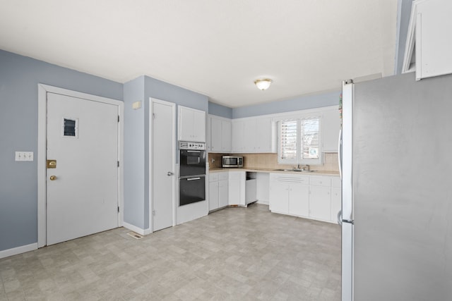 kitchen featuring light floors, stainless steel appliances, tasteful backsplash, light countertops, and white cabinets