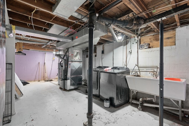 unfinished basement with a sink, washing machine and clothes dryer, and heating unit