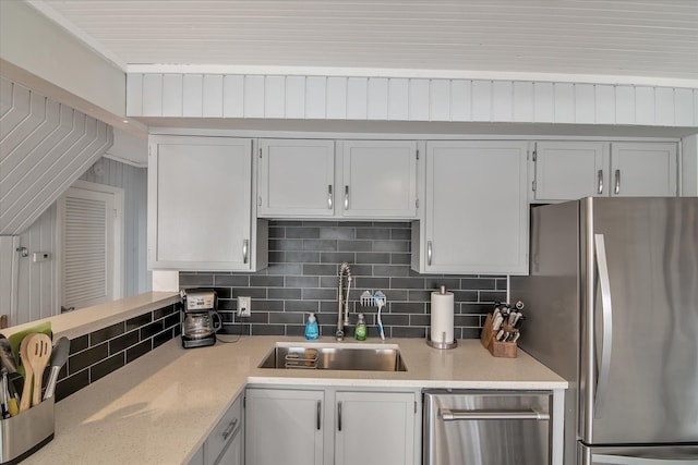 kitchen featuring backsplash, freestanding refrigerator, and a sink