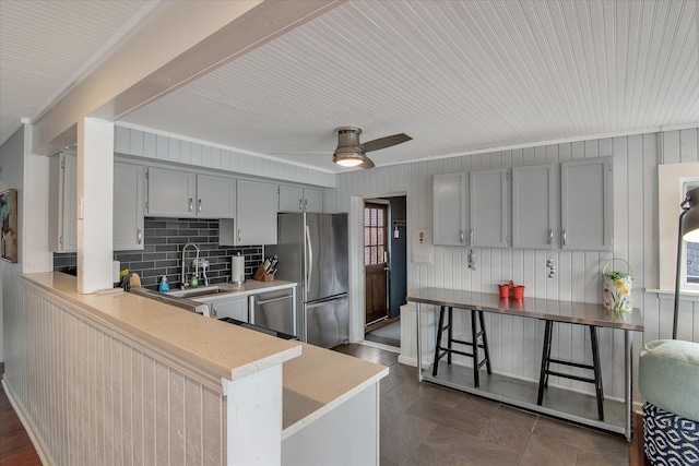 kitchen with a sink, a peninsula, gray cabinetry, and freestanding refrigerator