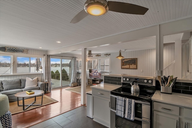 kitchen featuring dark wood-type flooring, gray cabinetry, double oven range, open floor plan, and ceiling fan