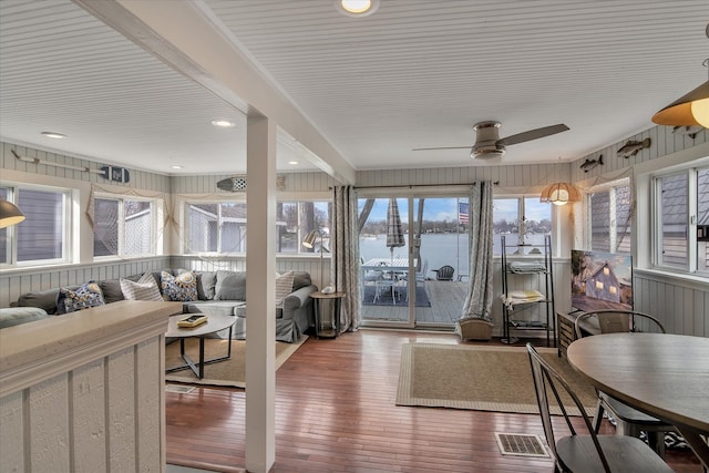 sunroom with a ceiling fan, visible vents, and a water view