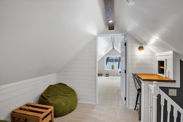 bonus room featuring wooden walls, light colored carpet, and vaulted ceiling