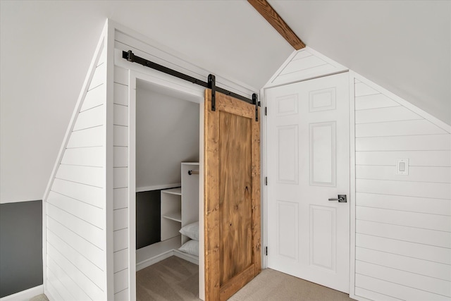 interior space featuring lofted ceiling with beams, a barn door, and light colored carpet