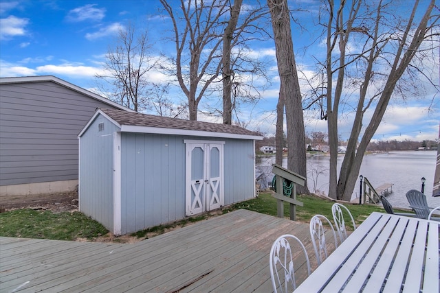 wooden terrace featuring a storage shed, a water view, and an outdoor structure