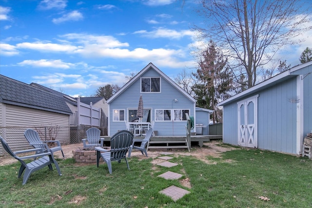 rear view of property with a wooden deck, a lawn, an outdoor structure, and an outdoor fire pit