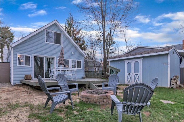 rear view of house featuring a yard, a fire pit, a deck, and an outdoor structure