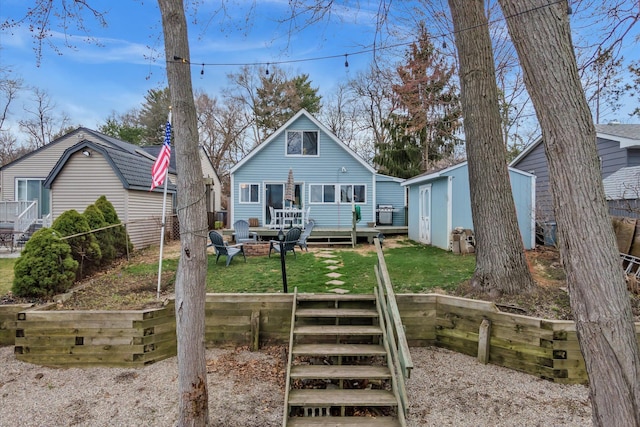 back of house featuring an outbuilding, fence, a wooden deck, a yard, and a fire pit