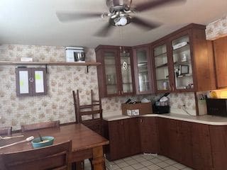 kitchen with glass insert cabinets, light countertops, ceiling fan, and wallpapered walls