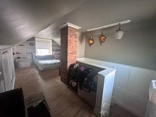 bedroom with vaulted ceiling, wainscoting, decorative columns, and a decorative wall