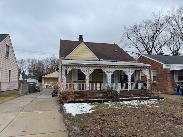 bungalow-style home with a shingled roof, a chimney, a gate, fence, and a porch