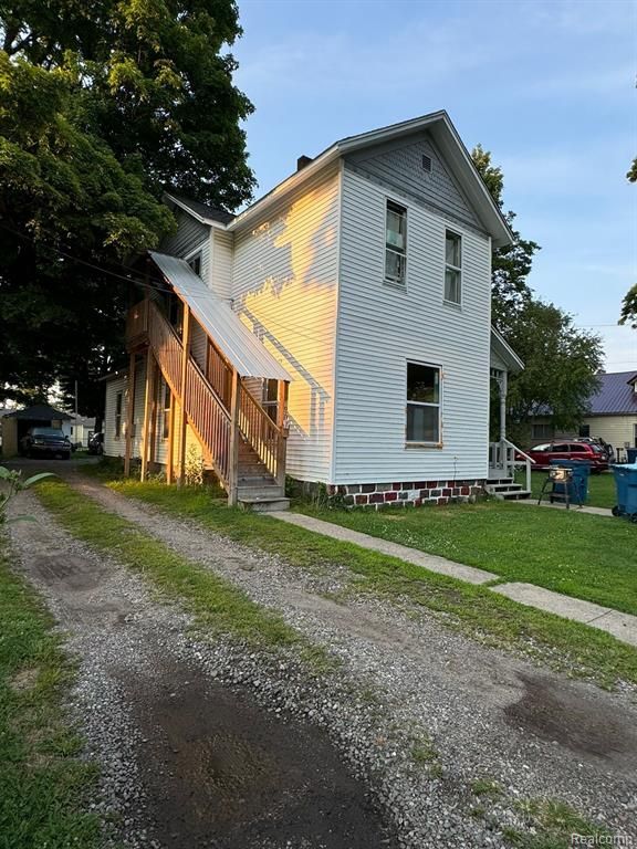 view of side of property with a yard, driveway, and a chimney